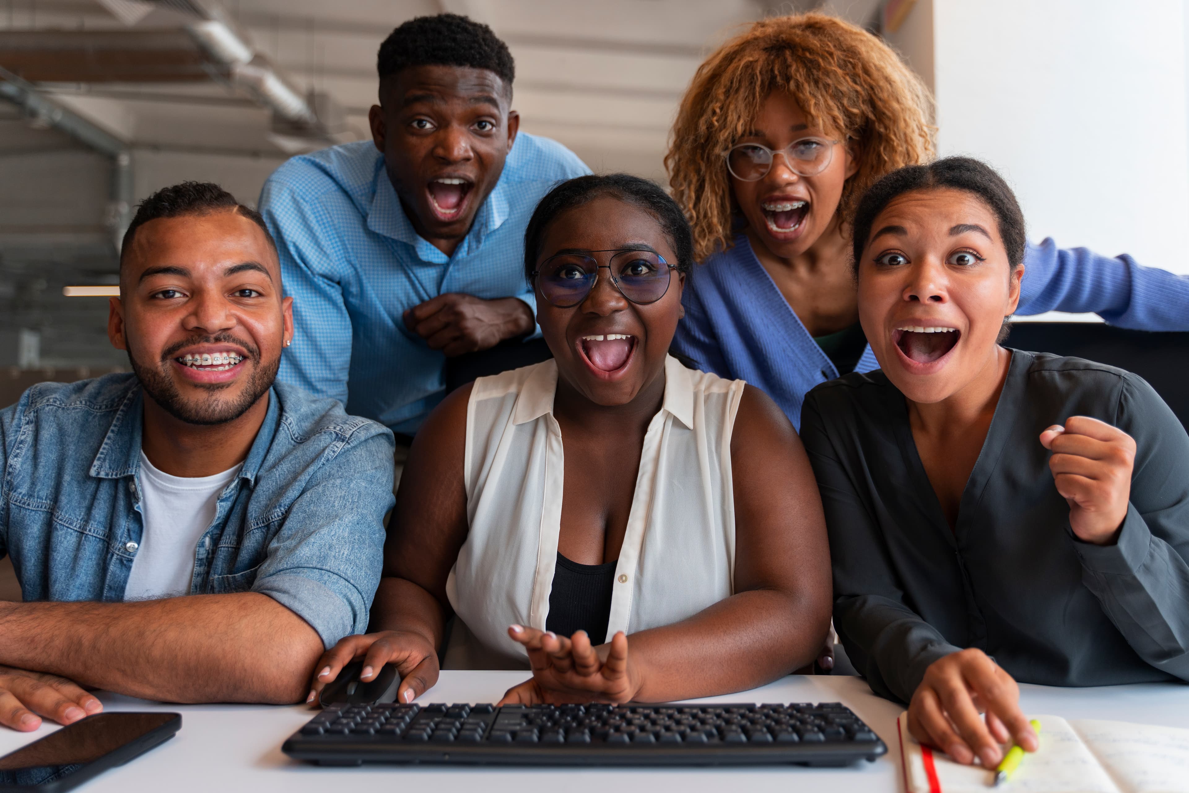 A team at a shared desk, cheering at a screen