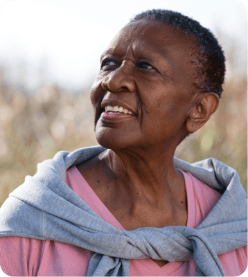 An older woman outdoors, looking up and smiling