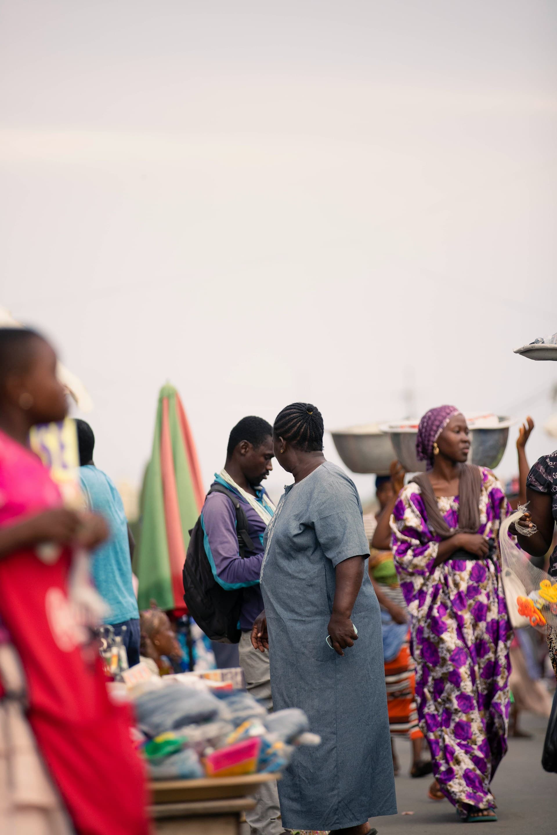 A busy market street, traders carrying basins and colorful fabric