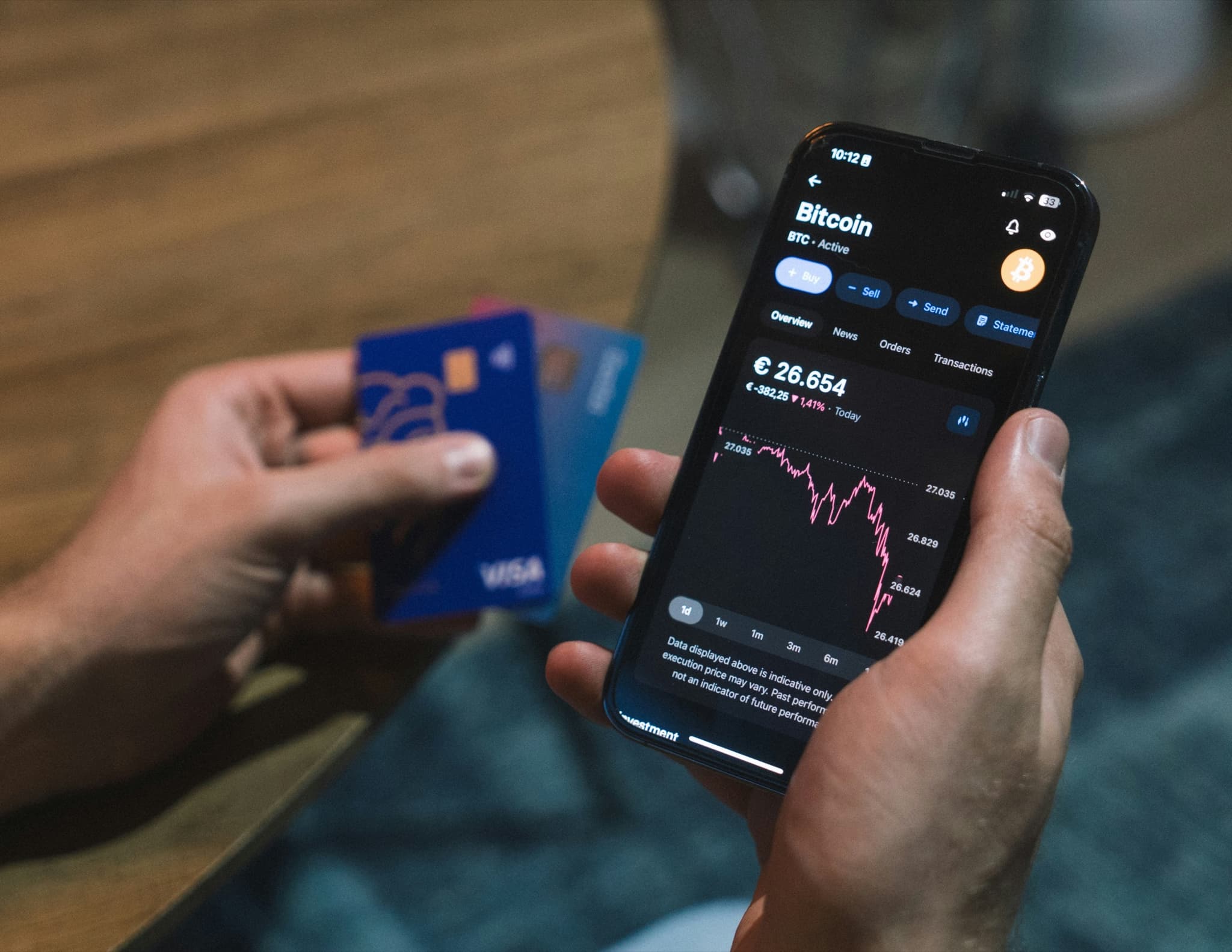 Hands holding a bank card beside a phone showing a rate on screen