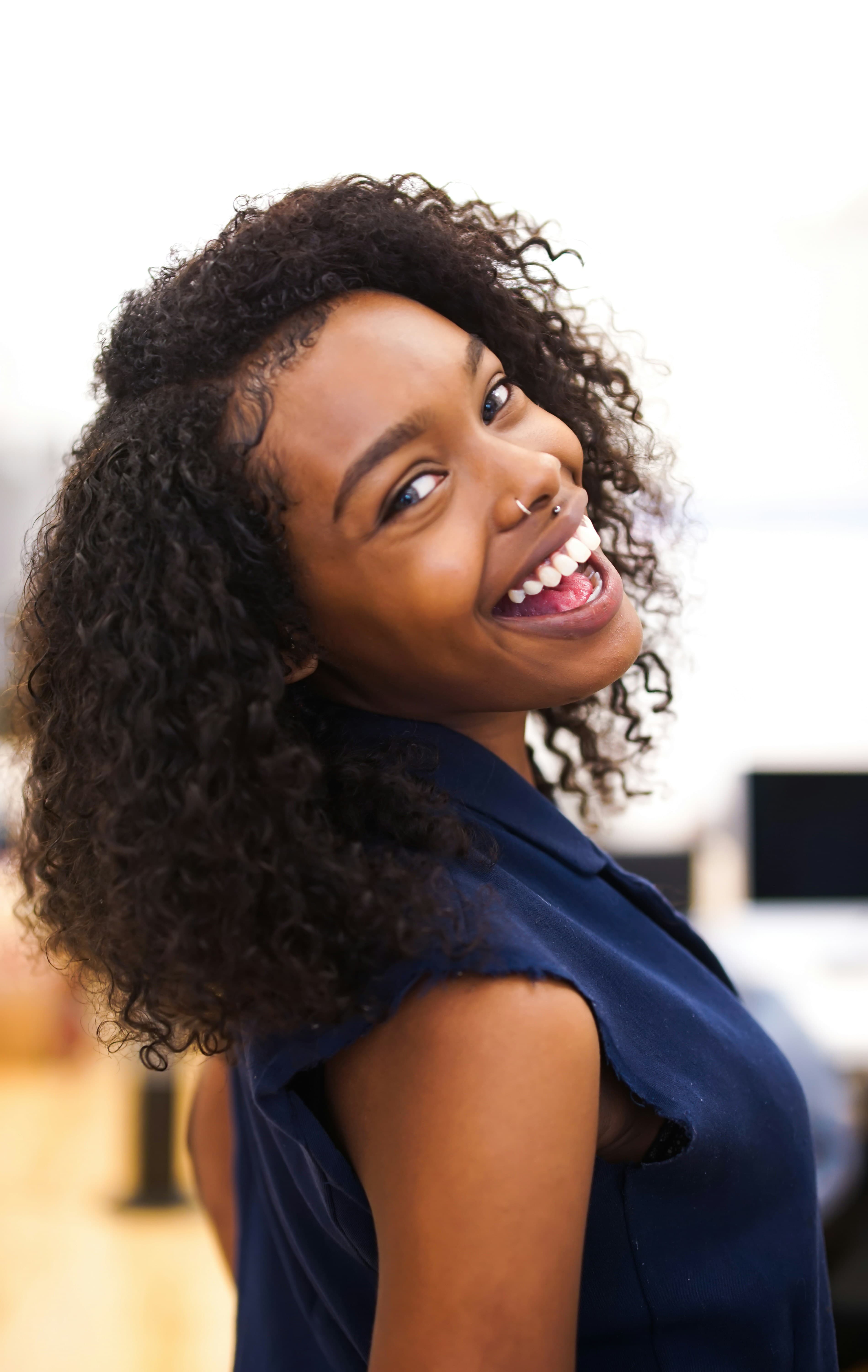 A woman with curly hair laughing over her shoulder