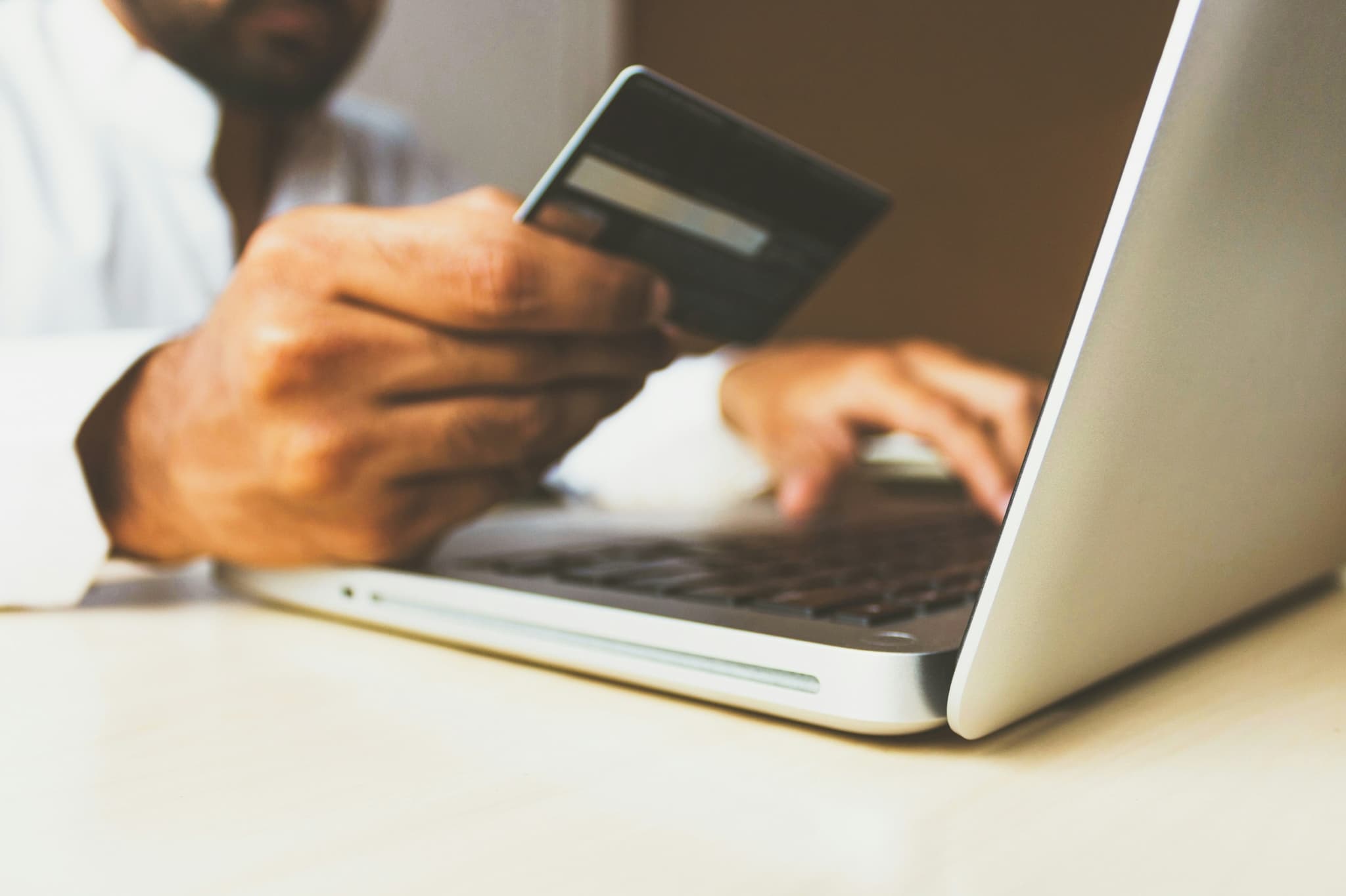 Someone paying on a laptop, card held in one hand while they type
