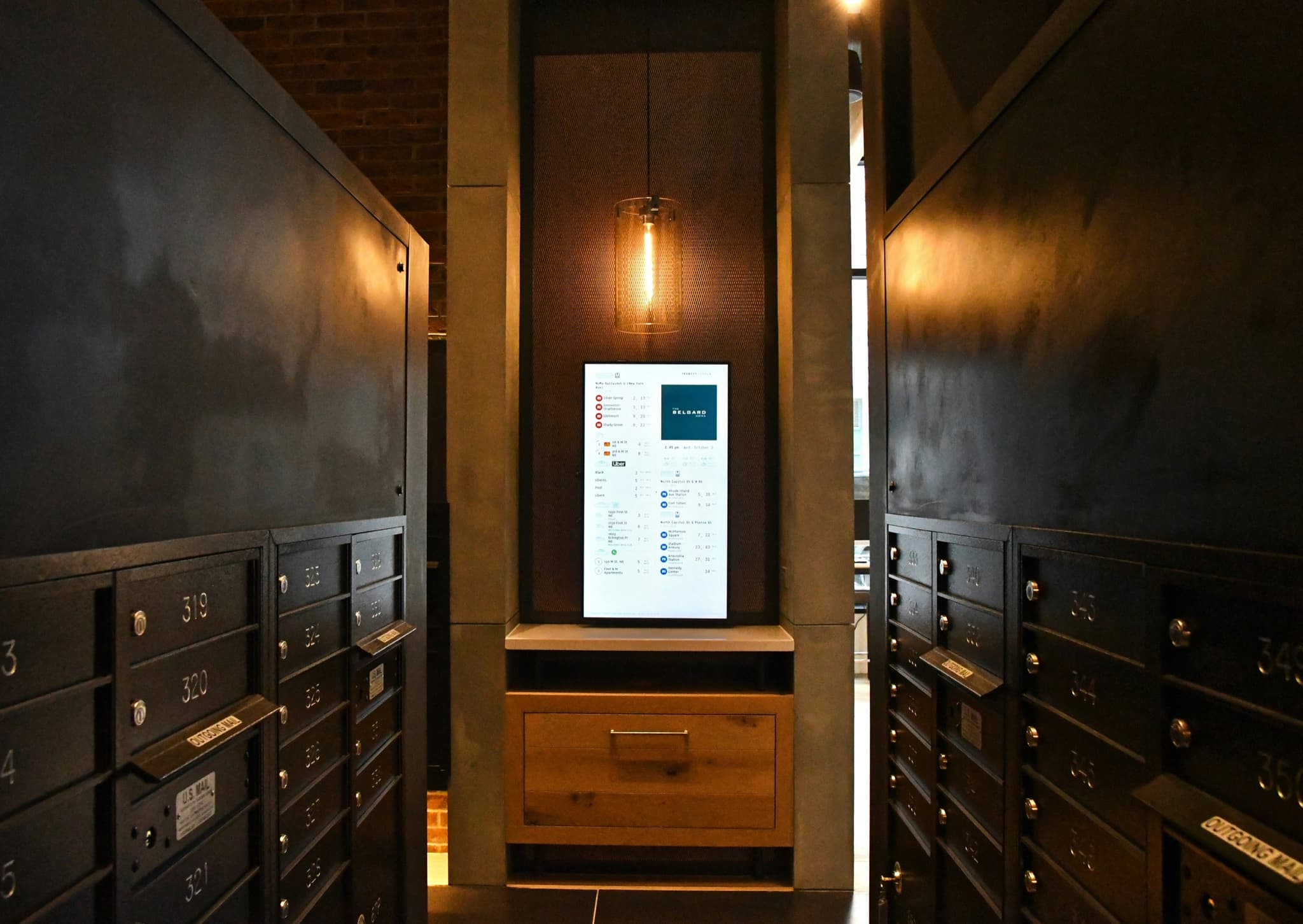 A wall of locked mailboxes beside a lit self-service terminal