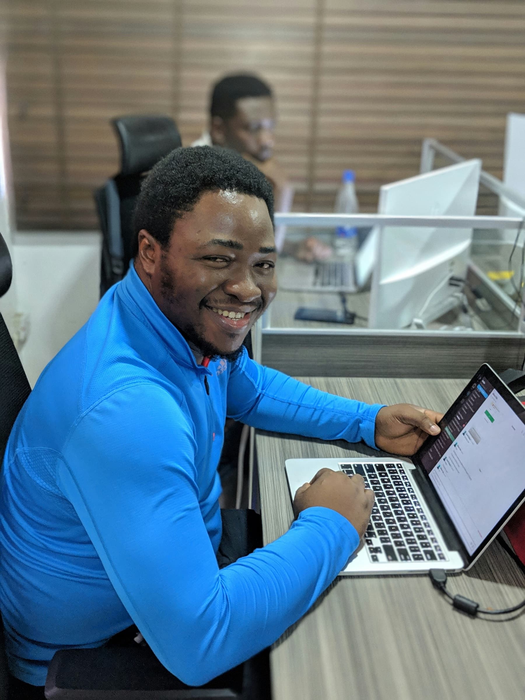 A man laughing over an open laptop at a work bench