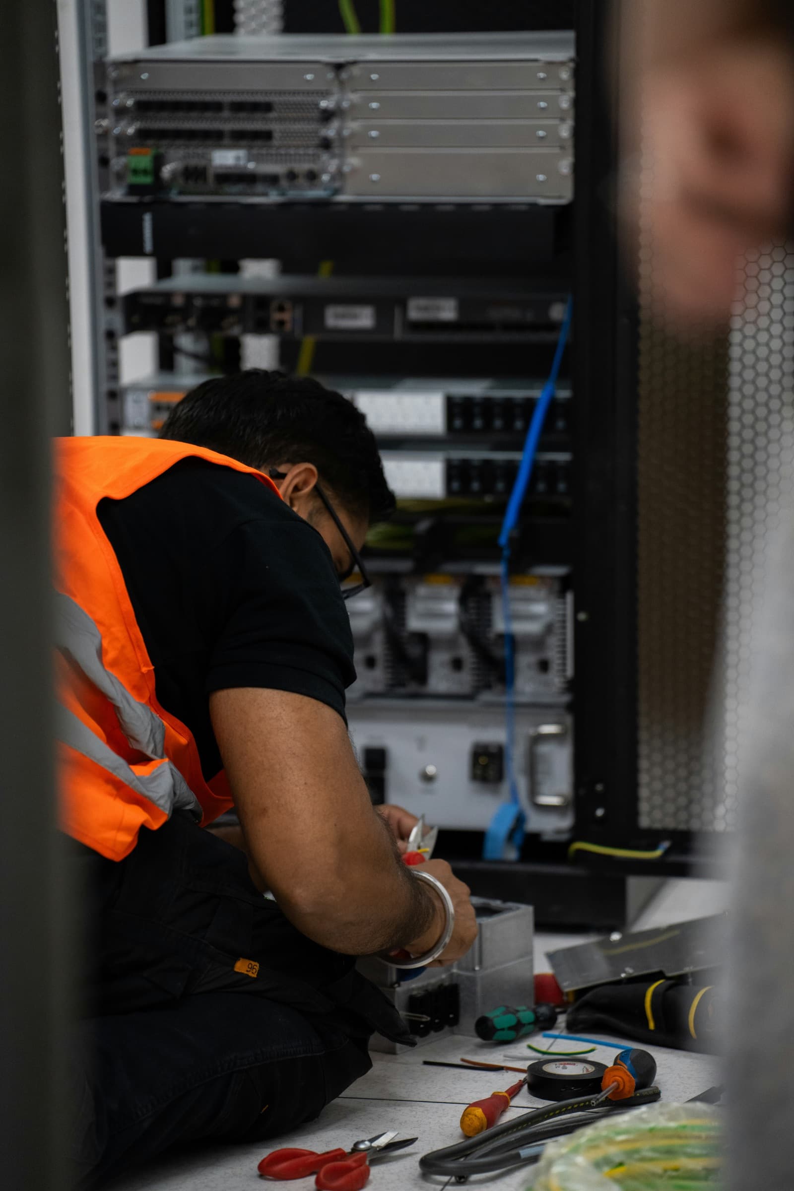 An operator in a high-visibility vest working a bank of controls