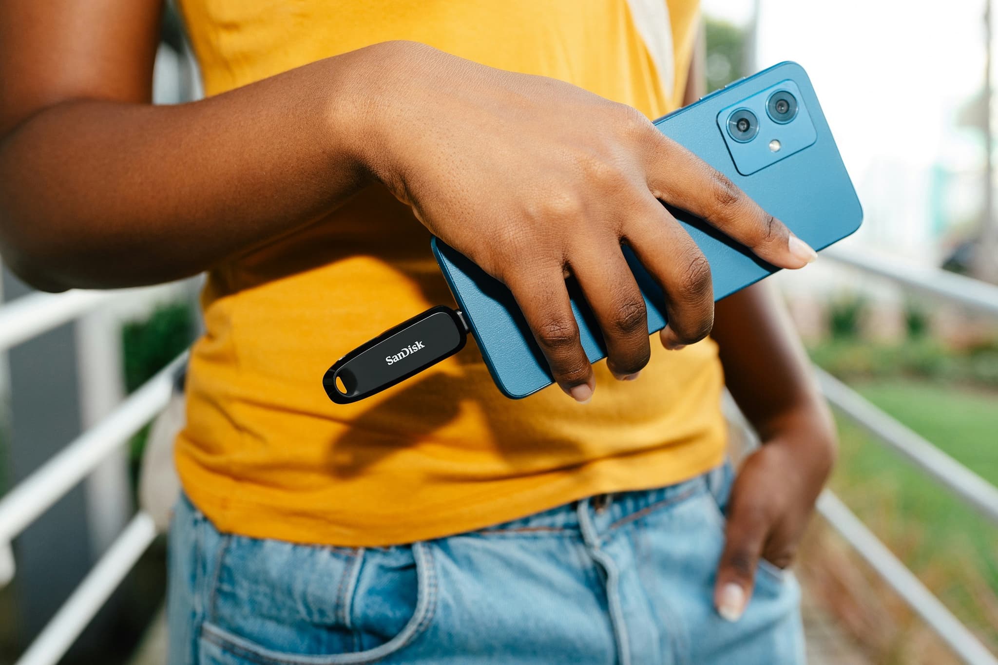 Someone in a yellow shirt sliding a phone into their back pocket